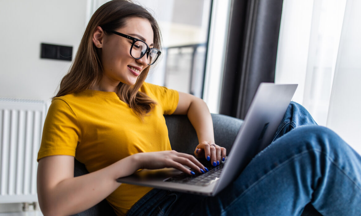 Retrato jovem mulher asiática usando laptop para trabalhar e sentada no sofá de uma sala de estar