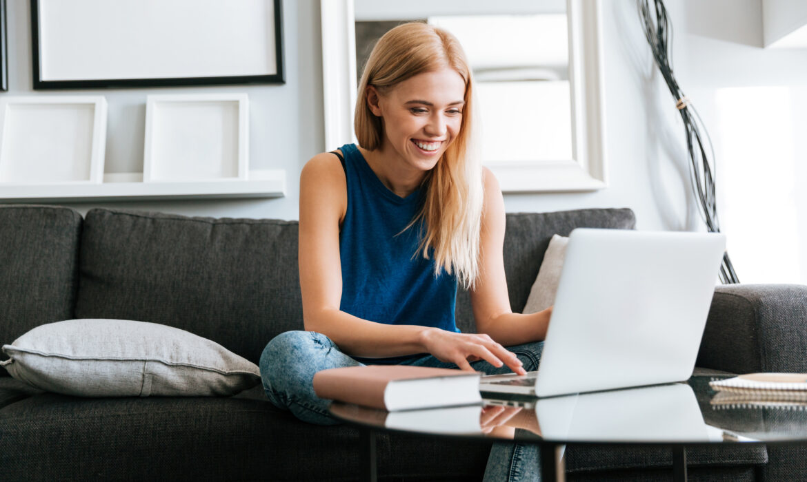 Retrato: Mulher jovem sentada no sofá e usando o laptop em uma sala de estar