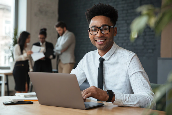 Indicadores de Desempenho Financeiro: Homem de negócios sorridente utiliza um notebook